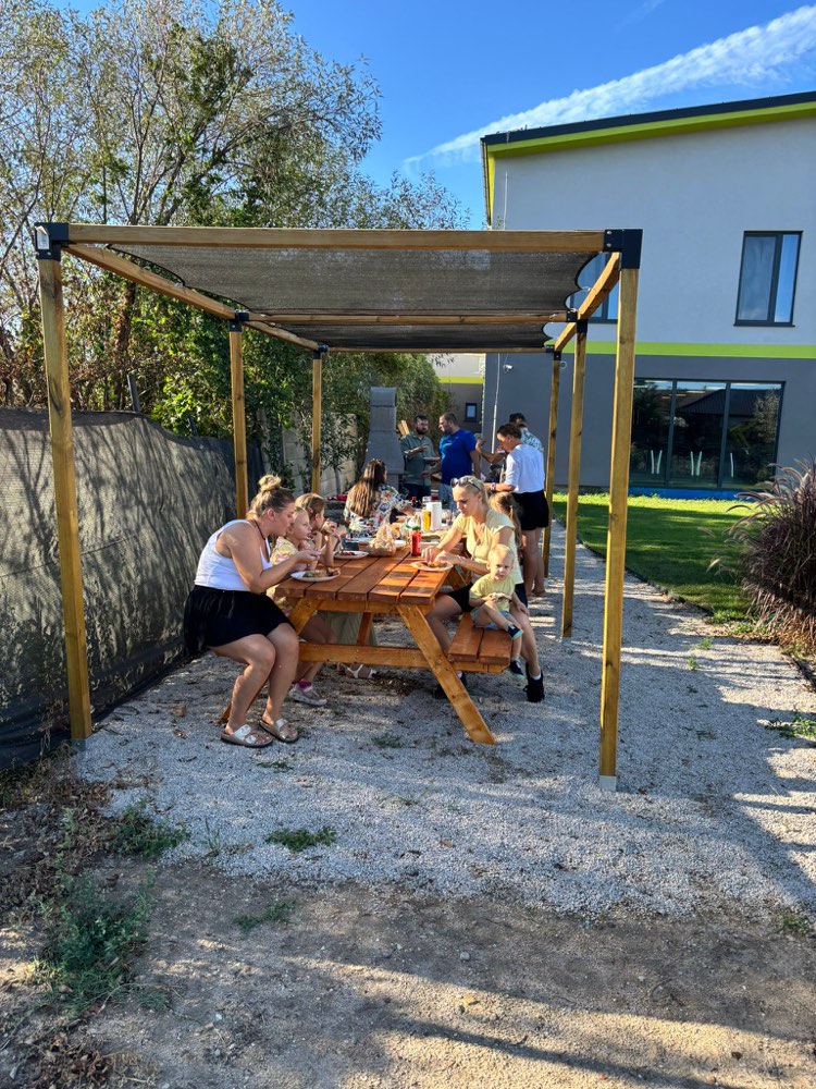 Pergola with a picnic table and guests eating